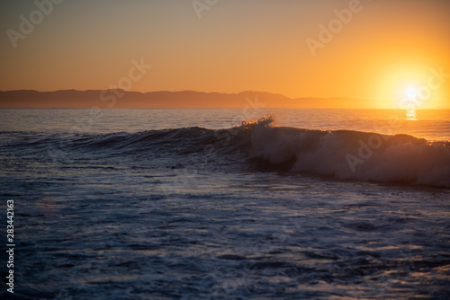 Waves crashing with sunrise in the background