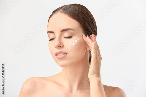 Woman with cosmetics on her face against white background