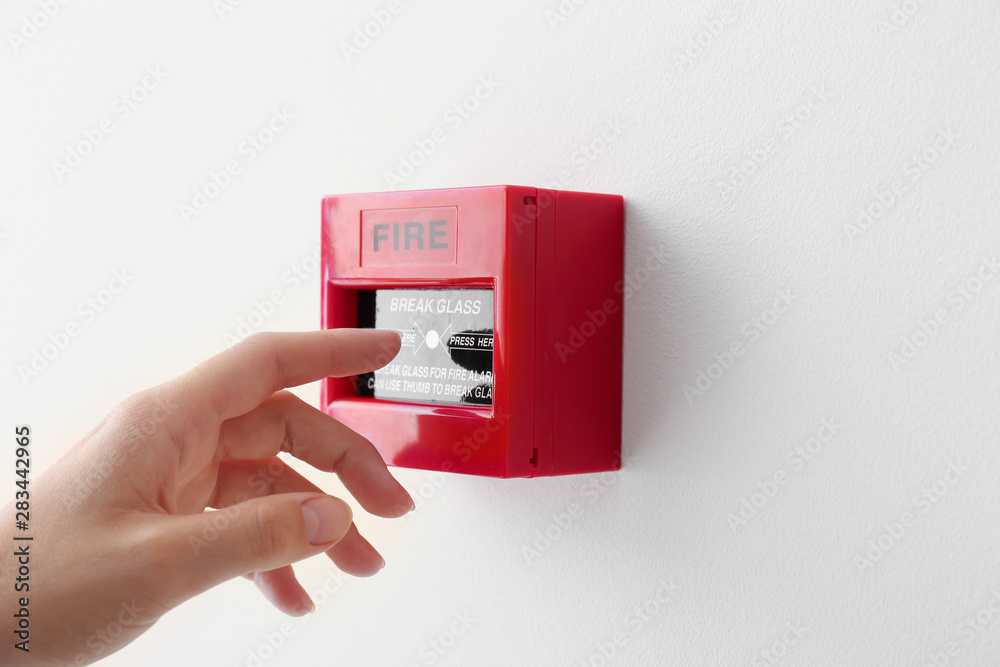 Woman using manual call point of fire alarm system Photos | Adobe Stock