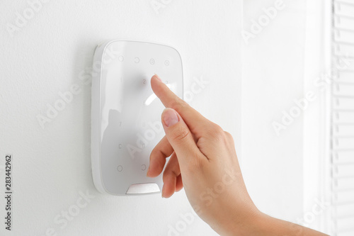 Woman entering code on panel of modern security system