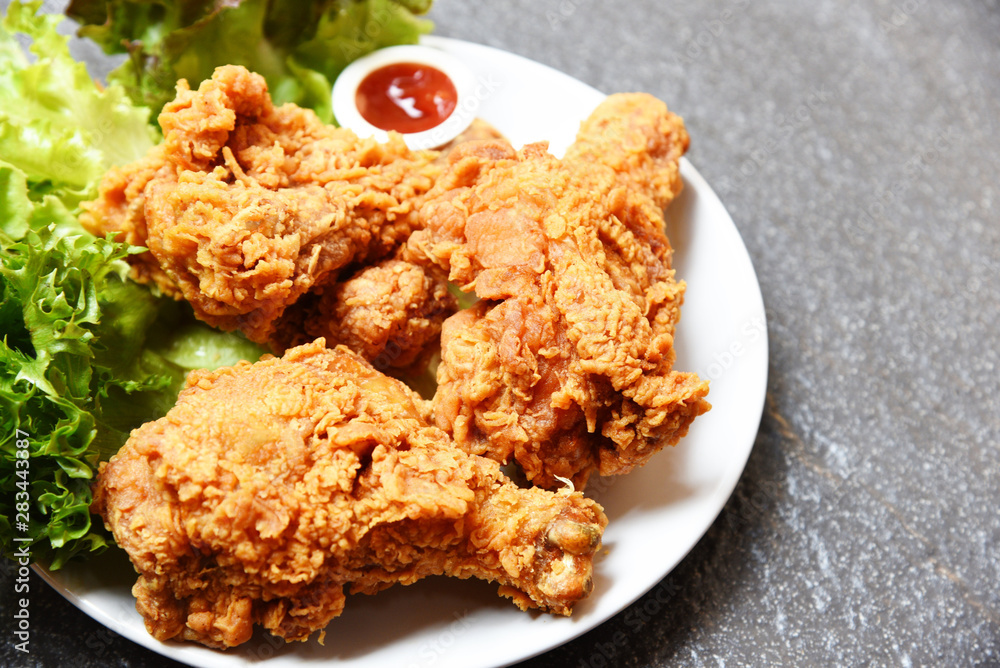 Fried chicken crispy on white plate with ketchup and salad lettuce vegetable on dark plate Fried chicken crispy on white plate with ketchup and salad lettuce vegetable on dark plate
