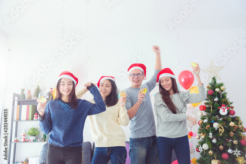 Three beautiful asian girls and a man celebrating Christmas or the New Year's Eve with wine