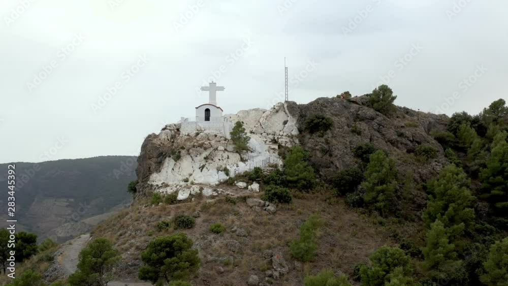 Tourists on rocky mountain top with tiny white church in Spain, low parallax drone Tourists on rocky mountain top with tiny white church in Spain, low parallax drone