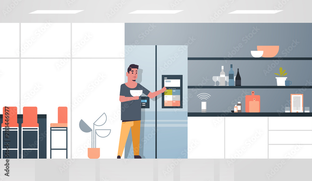 man touching refrigerator screen with smart speaker voice recognition activated digital assistant concept modern kitchen interior flat horizontal full length man touching refrigerator screen with smart speaker voice recognition activated digital assistant concept modern kitchen interior flat horizontal full length