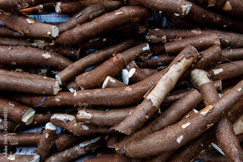 Large amount of unpeeled cassava being sold at a street fair. Top view.