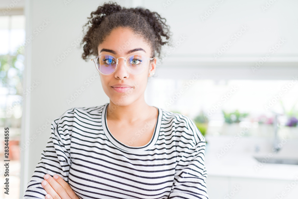 Beautiful young african american woman with afro hair wearing glasses Relaxed with serious expression on face. Simple and natural with crossed arms