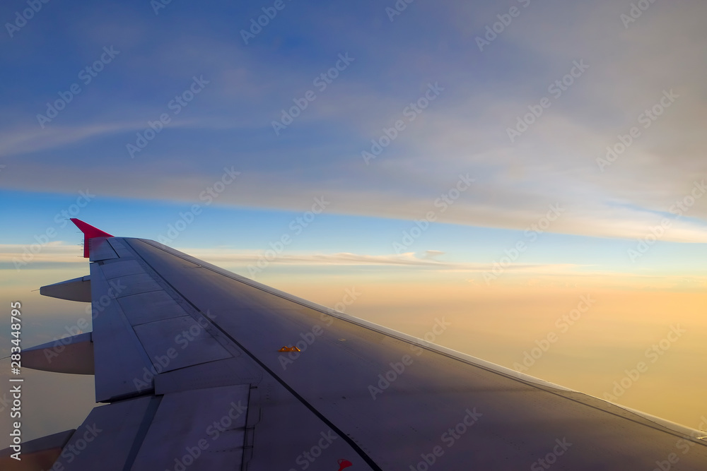 Flying and traveling, view from airplane window on the wing on sunset time