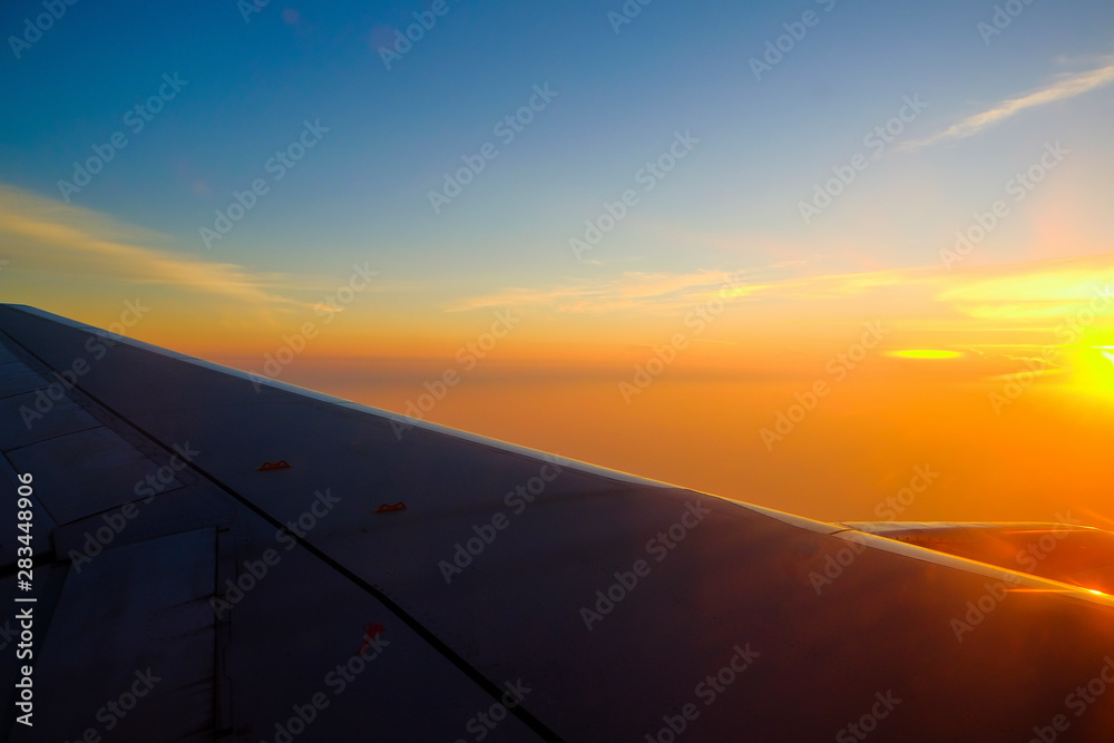 Fototapeta premium Flying and traveling, view from airplane window on the wing on sunset time