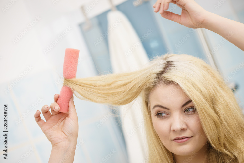 Fototapeta premium Blonde woman using hair rollers