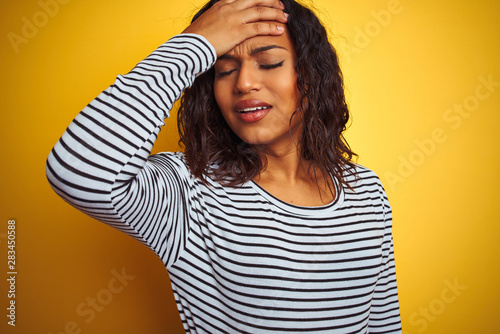 Transsexual transgender woman wearing striped t-shirt over isolated yellow background stressed with hand on head, shocked with shame and surprise face, angry and frustrated. Fear and upset