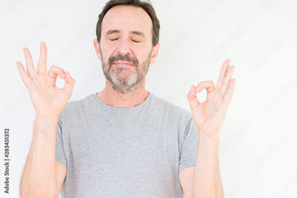 Handsome senior man over isolated background relax and smiling with eyes closed doing meditation gesture with fingers. Yoga concept. Handsome senior man over isolated background relax and smiling with eyes closed doing meditation gesture with fingers. Yoga concept.