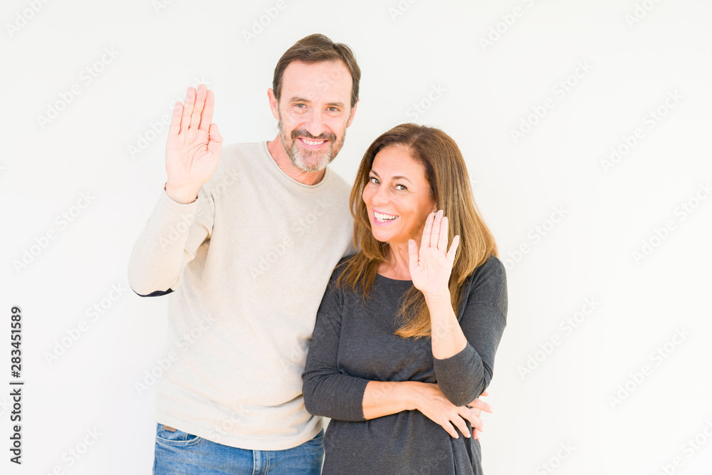 Beautiful middle age couple in love over isolated background Waiving saying hello happy and smiling, friendly welcome gesture Beautiful middle age couple in love over isolated background Waiving saying hello happy and smiling, friendly welcome gesture