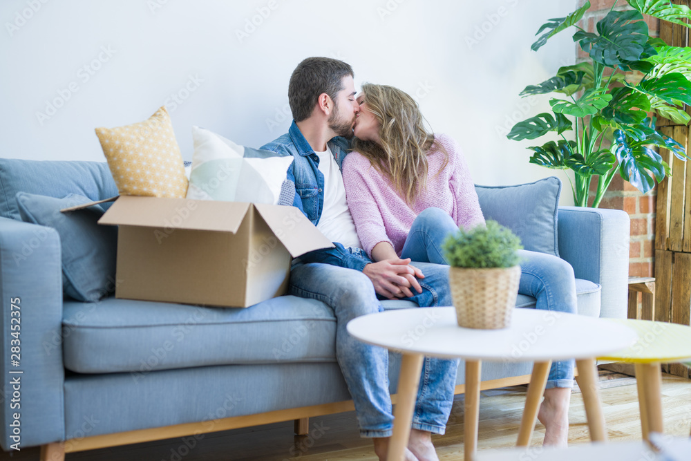 Young couple in love hugging sitting on the sofa very happy moving to a new home Young couple in love hugging sitting on the sofa very happy moving to a new home