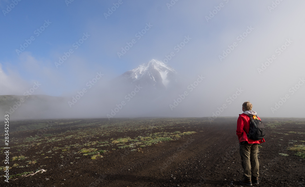 Symmetrical conus of Koryaksky (also known: Koryakskaya Sopka), an active volcano on the Kamchatka Peninsula in the Russian Far East from Avacha base camp. Slopes of volcanic hills in front.