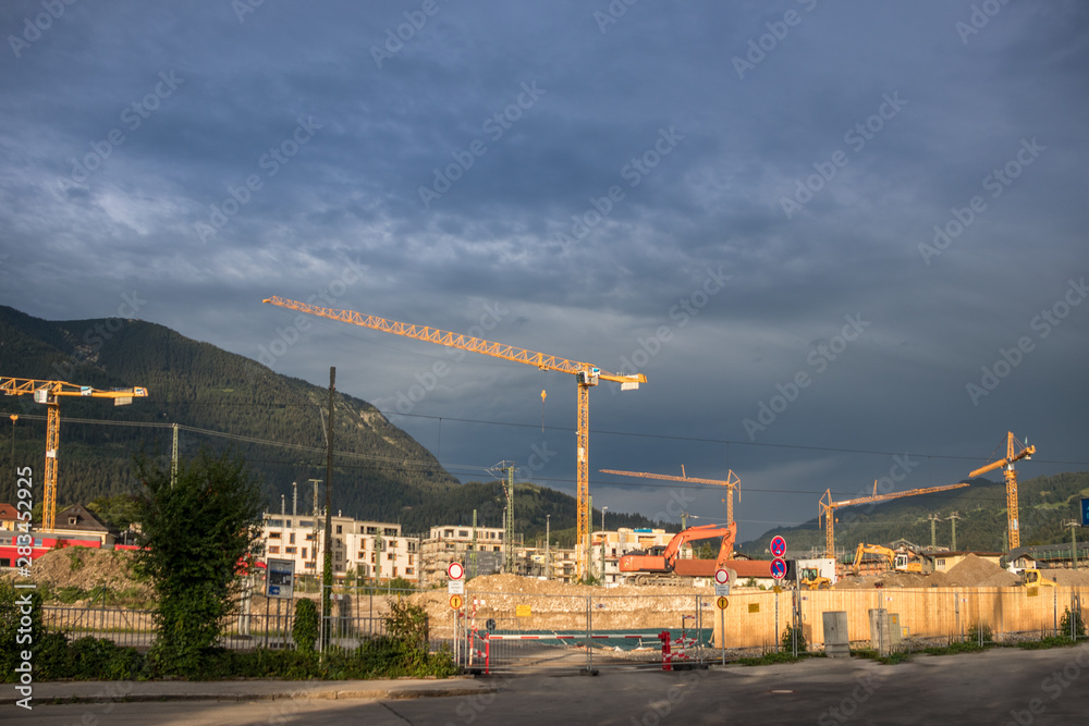 Baustelle mit Kränen nach Regen mit Bergen im Hintergrund Baustelle mit Kränen nach Regen mit Bergen im Hintergrund