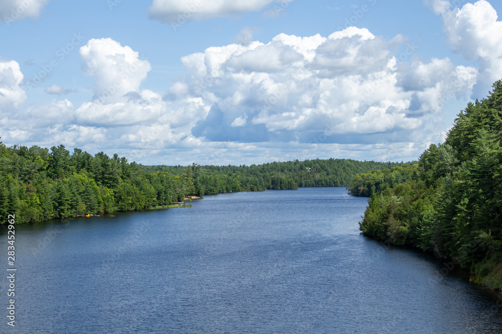 A river is viewed from a crossing with evergreen-rich forests on both shores. A river is viewed from a crossing with evergreen-rich forests on both shores.