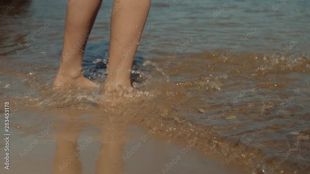 Woman Played With Water On Sand Beach At Sunset Slow Motion.Female Legs In Water, Woman Splashing And Playing With Feet Have Fun In Holiday Travel Vacation Adventure Enjoying Touching Sand And Waves. Woman Played With Water On Sand Beach At Sunset Slow Motion.Female Legs In Water, Woman Splashing And Playing With Feet Have Fun In Holiday Travel Vacation Adventure Enjoying Touching Sand And Waves.