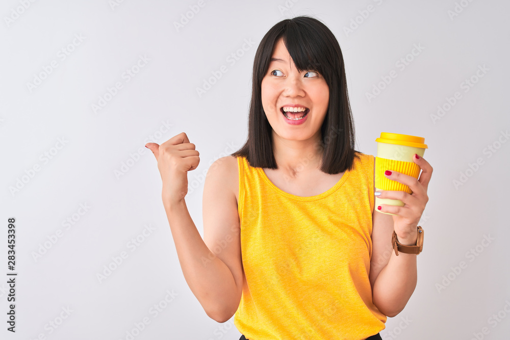 Young beautiful Chinese woman drinking take away coffee over isolated white background pointing and showing with thumb up to the side with happy face smiling Young beautiful Chinese woman drinking take away coffee over isolated white background pointing and showing with thumb up to the side with happy face smiling