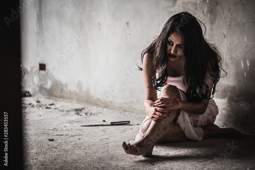 Fotografie Social Violence Concept - Psychosis woman sitting on the floor with a bloody knife