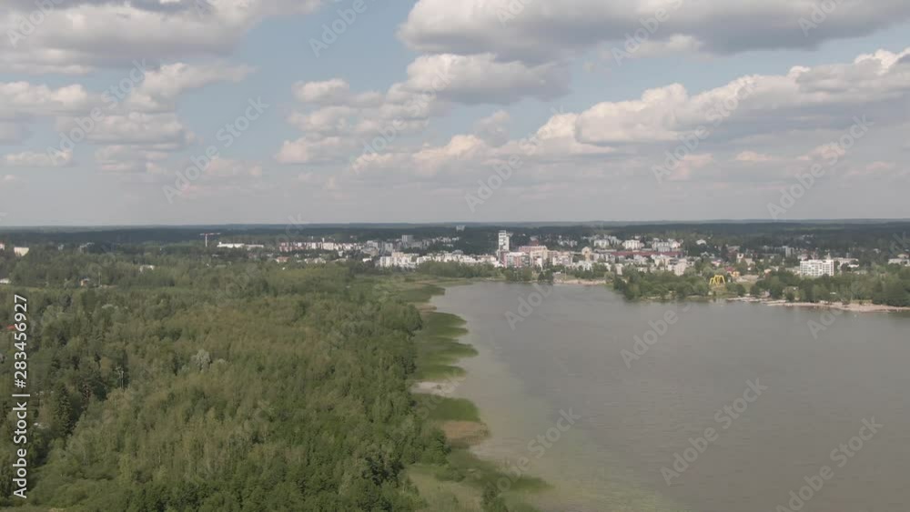 Lake and green forest near city. Flying over green trees and pond. Wild nature. Water. Horizon. Arial drone shot. Lake and green forest near city. Flying over green trees and pond. Wild nature. Water. Horizon. Arial drone shot.
