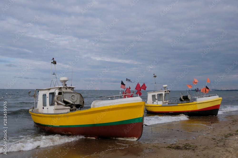 Wooden fishing boats on the beach of Baltic Sea in Sopot/Poland. Red flag poles for marking networks. Wooden fishing boats on the beach of Baltic Sea in Sopot/Poland. Red flag poles for marking networks.