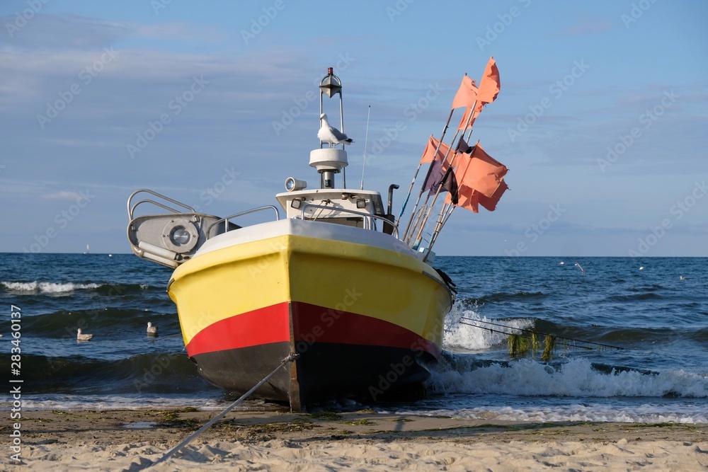Wooden fishing boat on the beach of Baltic Sea in Sopot/Poland. Red flag  poles for marking networks. Stock Photo