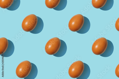 Brown eggs pattern on blue background. Creative layout.