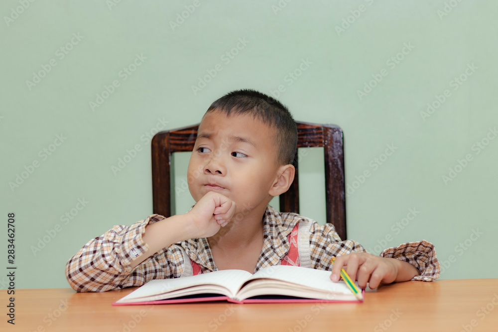 Happy little boy is sitting at the table and thinking Happy little boy is sitting at the table and thinking