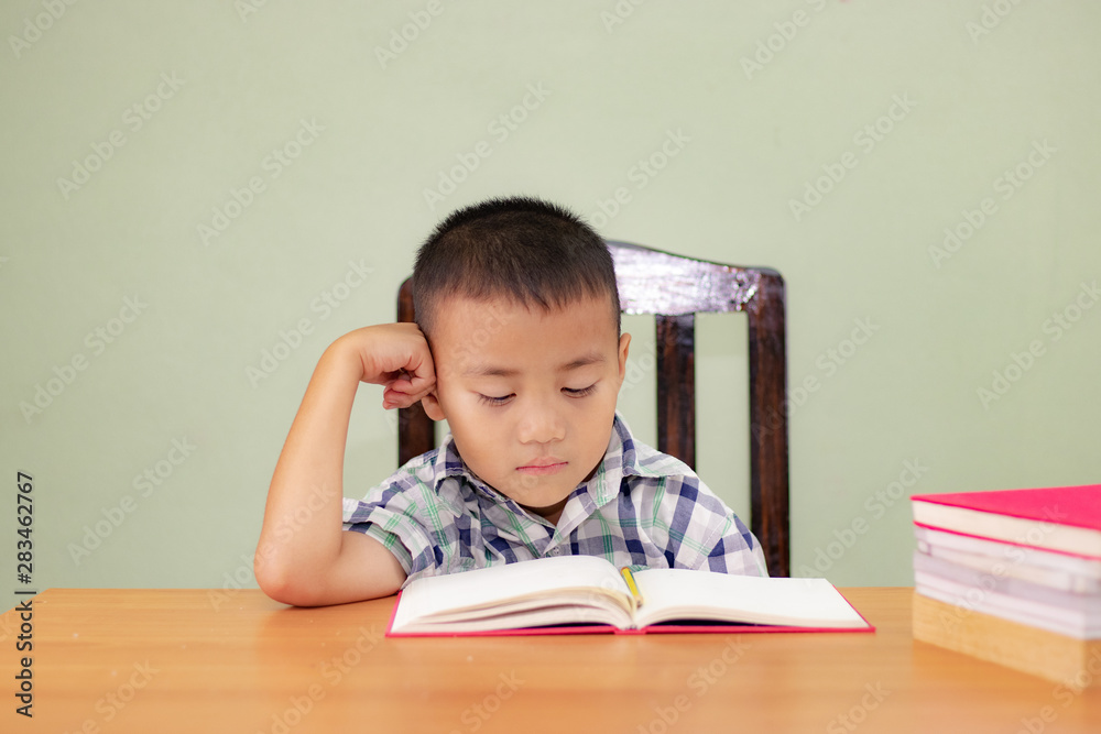 Happy little boy is sitting at the table and thinking Happy little boy is sitting at the table and thinking