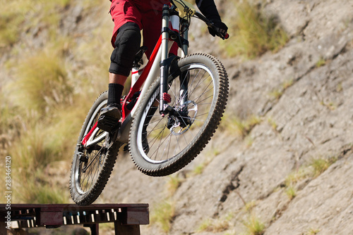 Professional athlete high jumping downhill on the mountain bike cross-country
