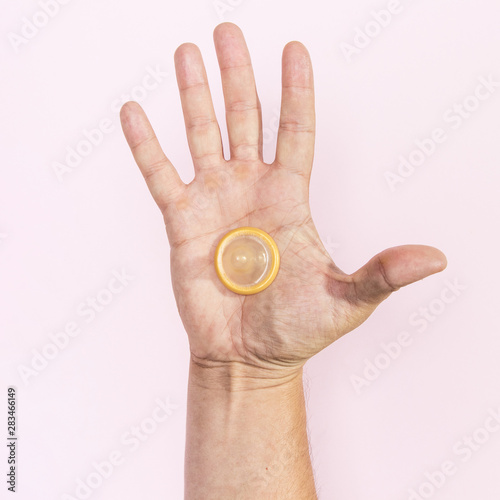 Close-up man hand holding a transparent condom