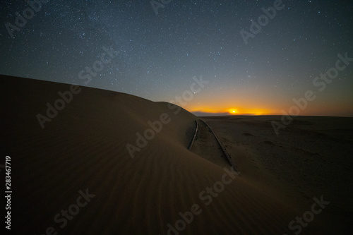 desert of namibia at night with orange sand dunes and starry sky.