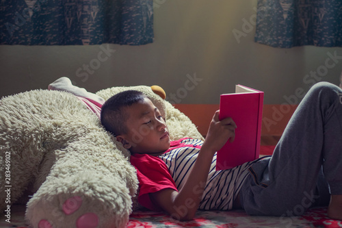 Happy Asian boy reading story book.