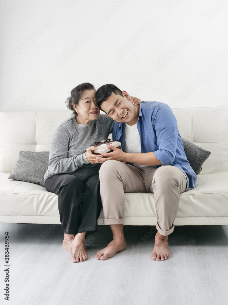 Happy Asian man giving gift box to his mother for Mother's Day celebration. Happy Asian man giving gift box to his mother for Mother's Day celebration.
