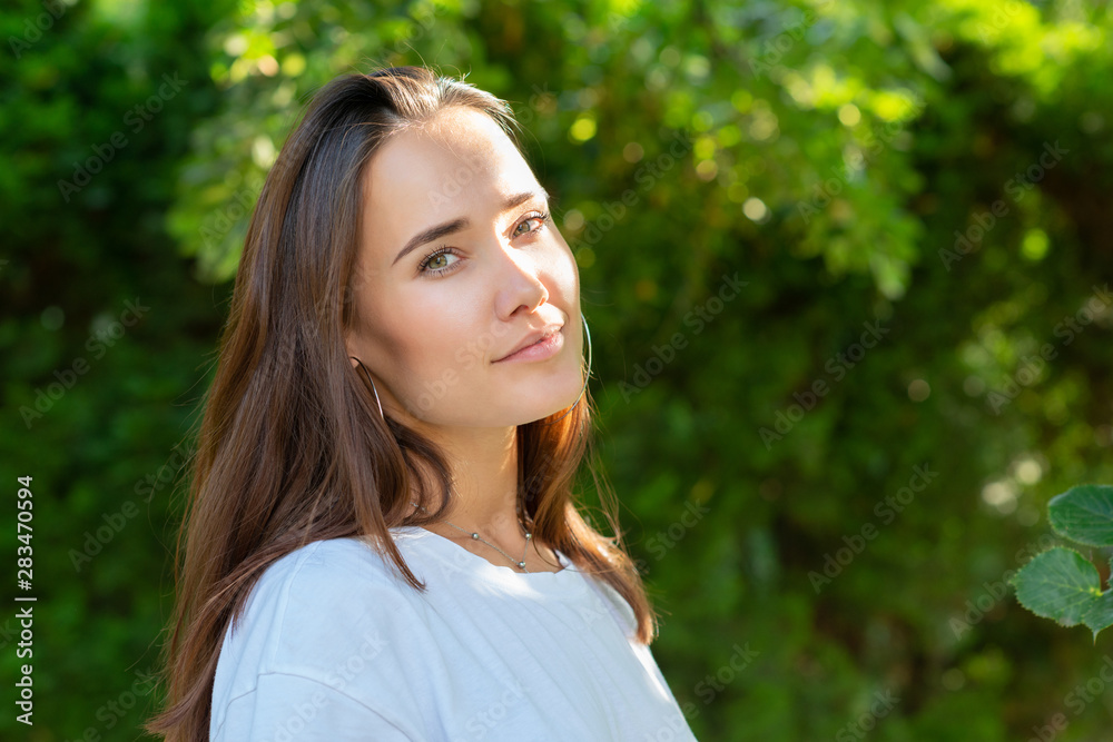 Portrait of beautiful young girl posing in summer park. Majestic woman's beauty. Youth, happiness, lifestyle.