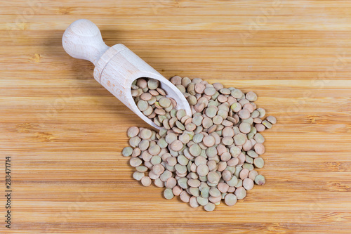 Whole brown lentil in wooden spice spoon and beside her photo