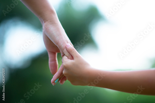Woman's and kid's hands. Mother lead his child, summer nature outdoor. Parenting, togetherness, help, union, childhood, trust, family concept. © Khorzhevska