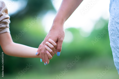 Woman's and kid's hands. Mother leads her child, summer nature outdoor. Parenting, togetherness, help, union, childhood, trust, family concept.
