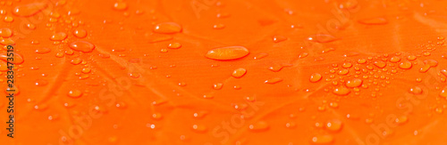 Raindrops on a tent of orange color as an abstract background