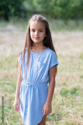 Pretty little girl posing summer nature outdoor in blue dress. Kid's portrait. Beautiful child's face