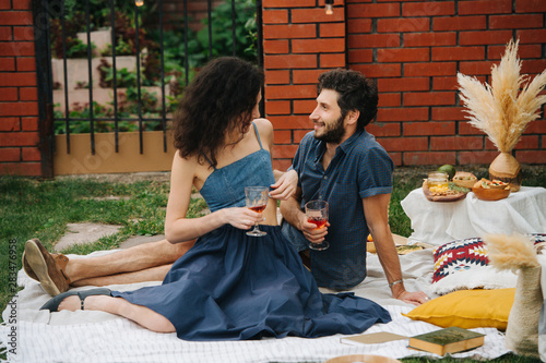 Fotografia Couple in love, drinking rose wine, having picnic on lawn in their courtyard