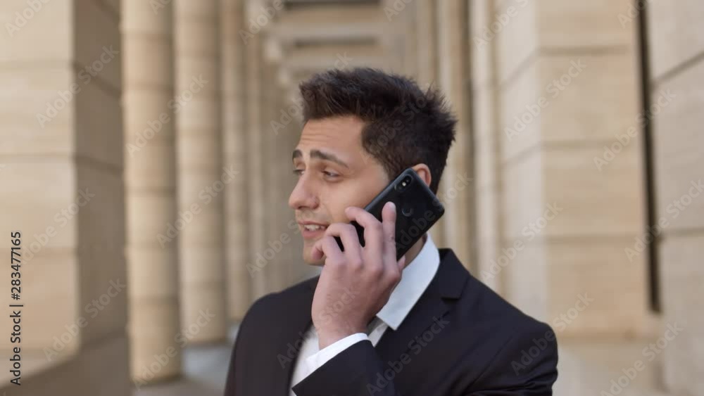 Close up of young mixed-race handsome businessman standing outside and talking on telephone Close up of young mixed-race handsome businessman standing outside and talking on telephone
