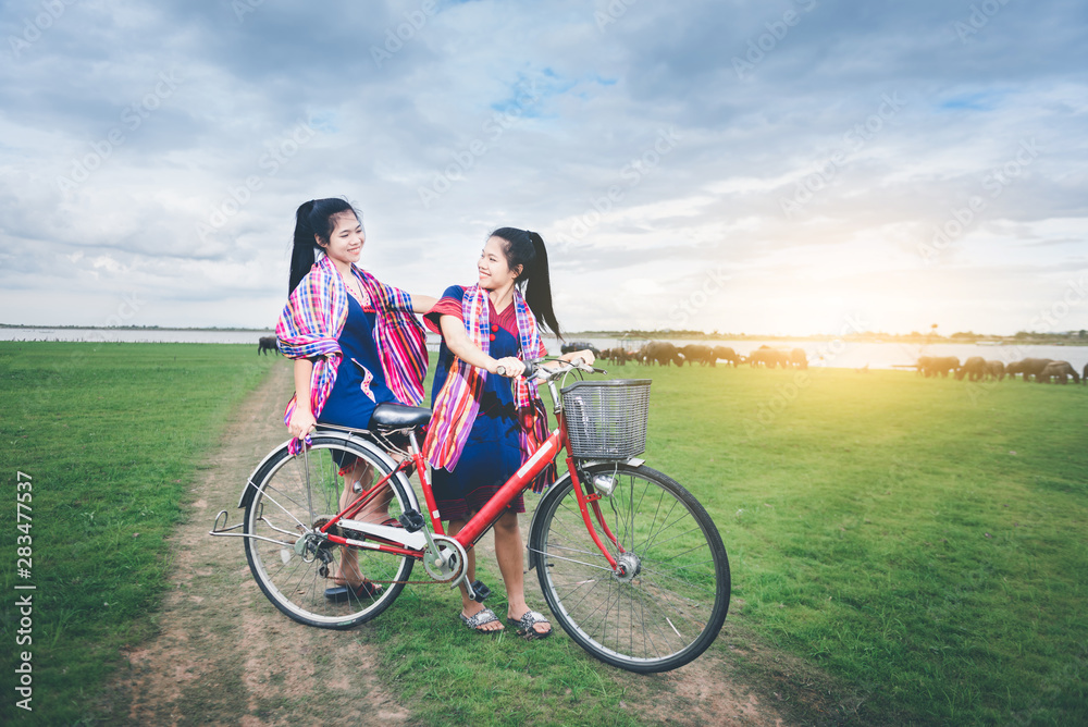 Beautiful Asian girls enjoy travel at countryside of Thailand by riding on bicycle