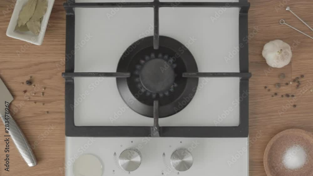 Person turns on gas stove and puts metal pan with water on it Person turns on gas stove and puts metal pan with water on it