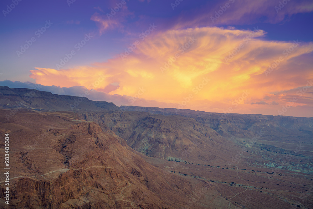 Mountain nature landscape. View of the valley from the mountain. The Judean Desert in the early morning. Beautiful cloud over the mountains. Beautiful sunrise over Masada fortress. Israel.