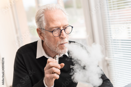 Obraz na płótnie Senior man smoking electronic cigarette