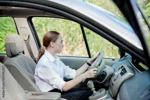 Close up portrait of pleasant looking female with glad positive expression, being satisfied with unforgettable journey by car, sits on driver s seat. People, driving, transport concept