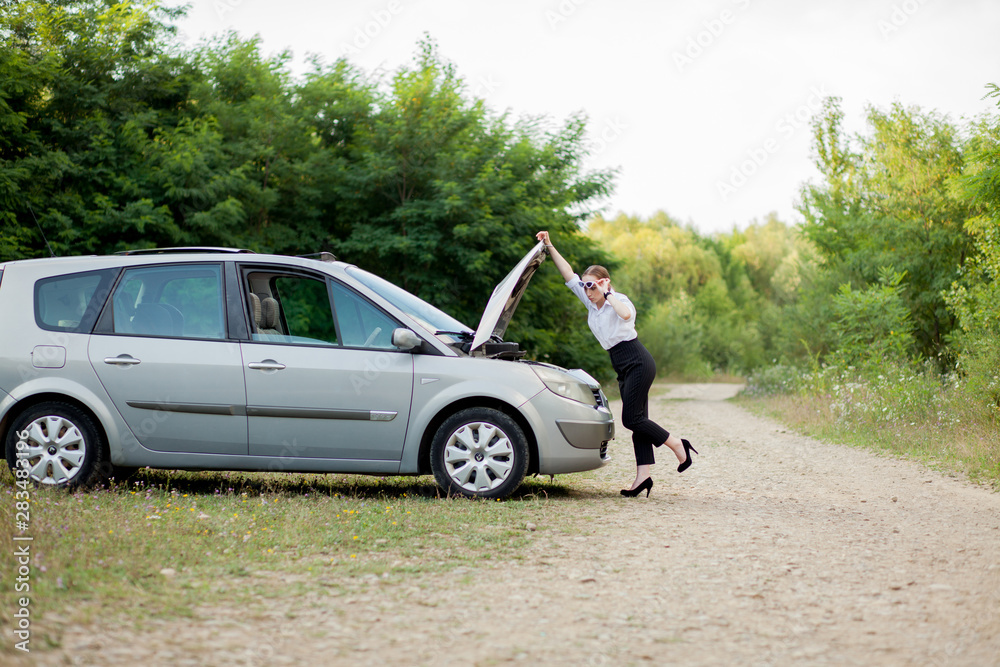 Young woman by the roadside after her car has broken down She opened the hood to see the damage Young woman by the roadside after her car has broken down She opened the hood to see the damage