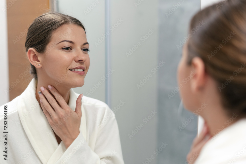 Woman in bathrobe looking in mirror at bathroom Woman in bathrobe looking in mirror at bathroom