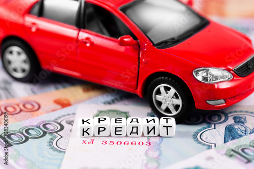 finance concept in blocks with word Loans (in Russian language) and closeup red car on the Russian rubles